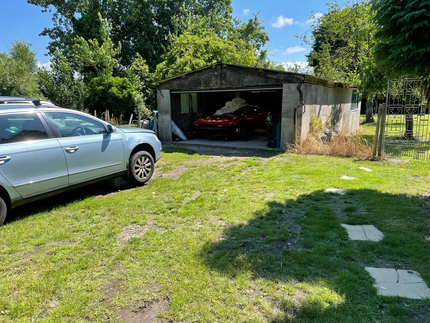 The plot before work started: an old sectional concrete garage on rough grass, with trees behind