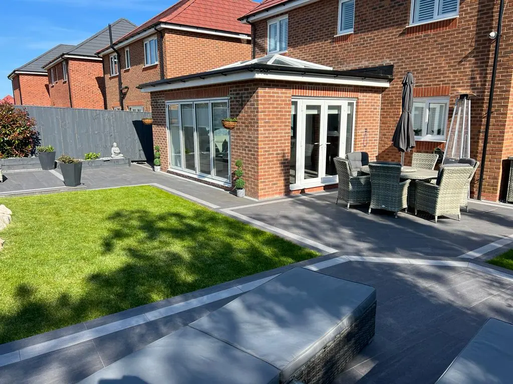 A completed single-storey orangery extension with a glazed lanternlight roof on a red brick house, with patio and garden